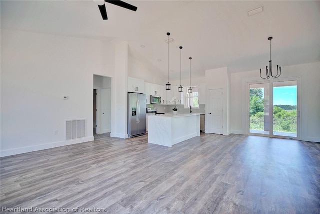 kitchen with pendant lighting, a kitchen island, white cabinetry, and stainless steel appliances