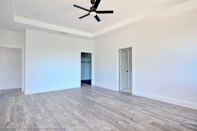 empty room featuring light hardwood / wood-style floors, a raised ceiling, and ceiling fan