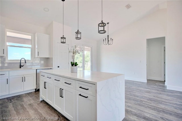 kitchen with decorative backsplash, pendant lighting, a center island, and white cabinetry