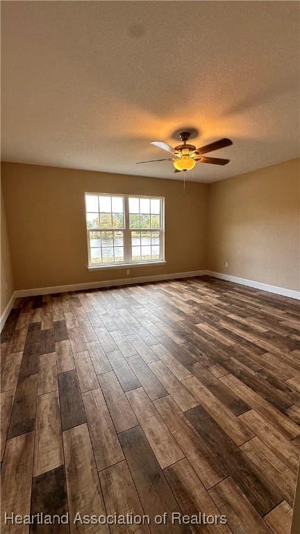 spare room with a textured ceiling, dark hardwood / wood-style floors, and ceiling fan