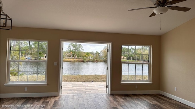 doorway with a wealth of natural light, a water view, wood-type flooring, and ceiling fan