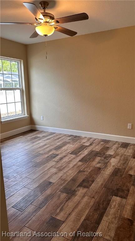 empty room with ceiling fan and dark wood-type flooring