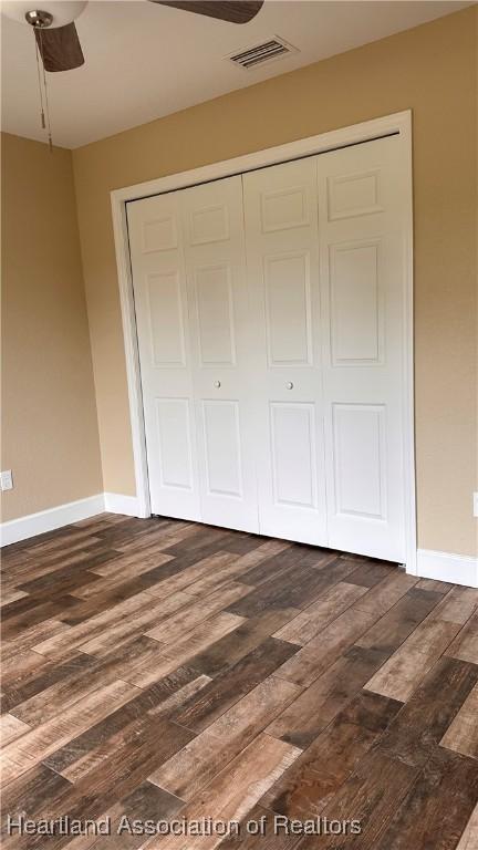 unfurnished bedroom featuring a closet, dark wood-type flooring, and ceiling fan