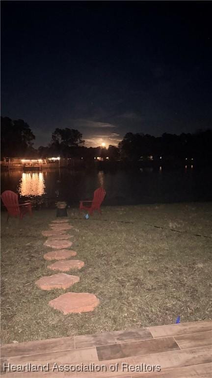 yard at night featuring a water view