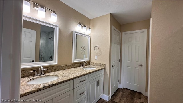 bathroom with walk in shower, vanity, a textured ceiling, and hardwood / wood-style flooring