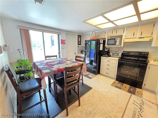 4618 Lafayette Ave, Sebring, FL 33875 - kitchen with black appliances, under cabinet range hood, light countertops, and cream cabinets