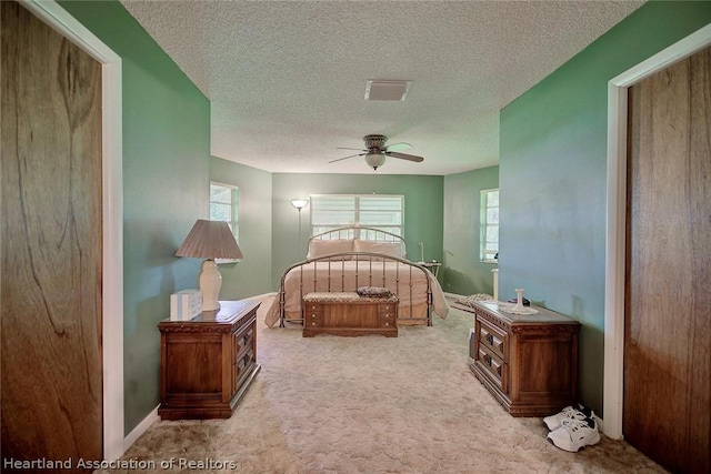 carpeted bedroom with ceiling fan and a textured ceiling