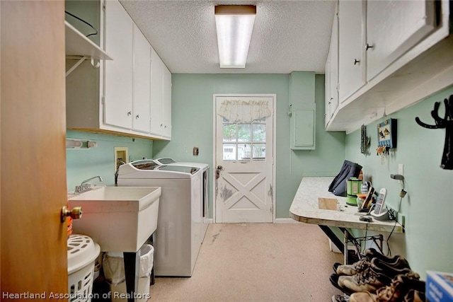 washroom featuring independent washer and dryer, sink, a textured ceiling, cabinets, and light carpet