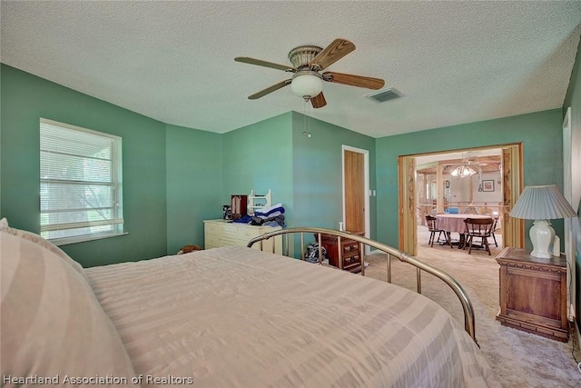 carpeted bedroom featuring ceiling fan and a textured ceiling