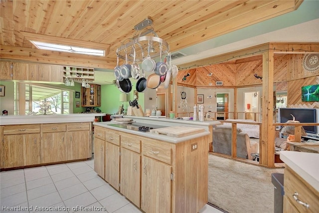 kitchen with light tile patterned floors, a center island, light brown cabinets, black electric cooktop, and wood ceiling