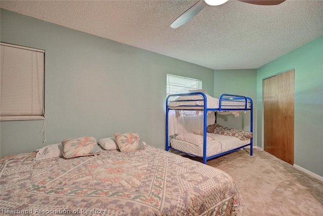 bedroom with ceiling fan, carpet floors, and a textured ceiling