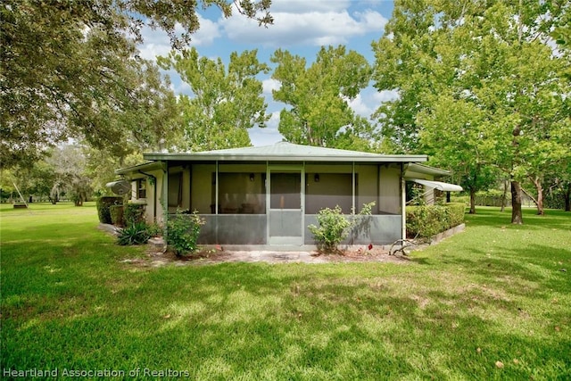 rear view of house with a yard and a sunroom