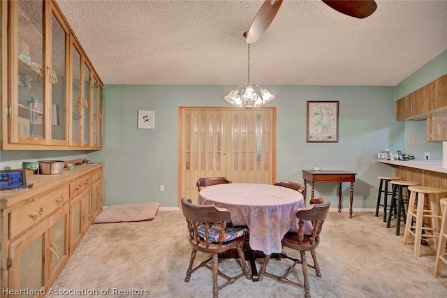 dining area featuring ceiling fan with notable chandelier, light carpet, and a textured ceiling