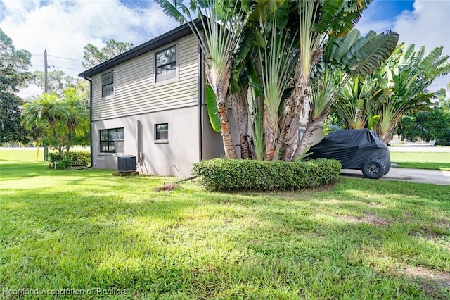 view of property exterior with a yard and central AC