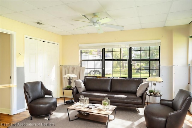 living room with ceiling fan, a paneled ceiling, and hardwood / wood-style flooring