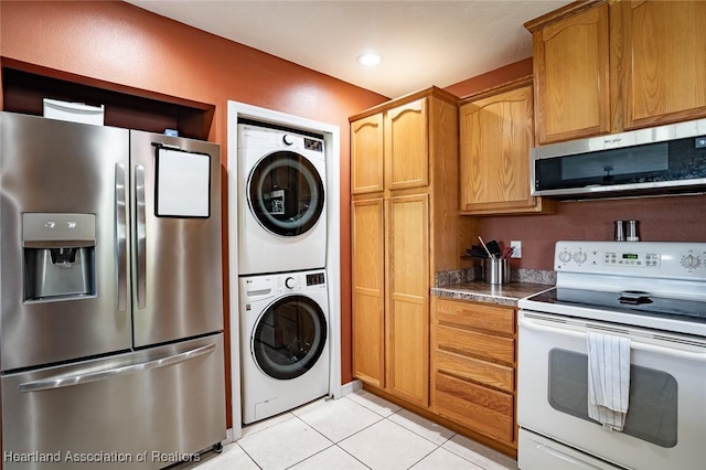 kitchen with stainless steel appliances, stacked washing maching and dryer, and light tile patterned floors