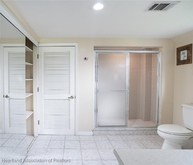 bathroom featuring tile patterned flooring, a shower with door, and toilet