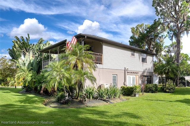 rear view of property with a balcony and a yard