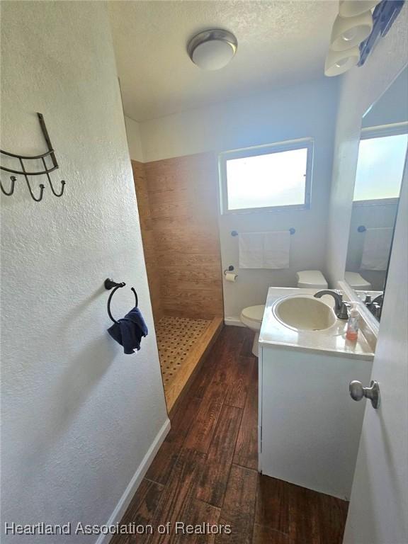 908 Taseschee Dr, Sebring, FL 33870 - full bath with a tile shower, vanity, wood finished floors, and toilet