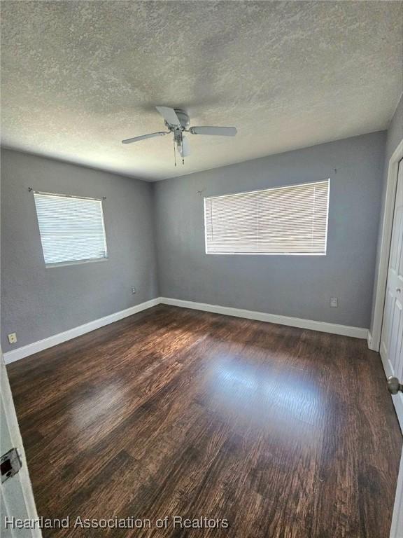 908 Taseschee Dr, Sebring, FL 33870 - empty room with dark wood-style floors, a textured ceiling, a ceiling fan, and baseboards