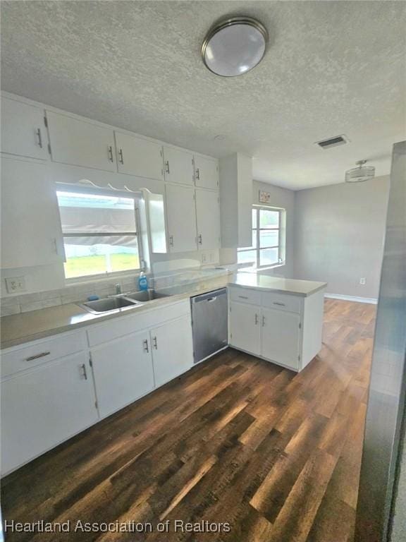 908 Taseschee Dr, Sebring, FL 33870 - kitchen with stainless steel dishwasher, dark wood finished floors, a textured ceiling, a peninsula, and a sink