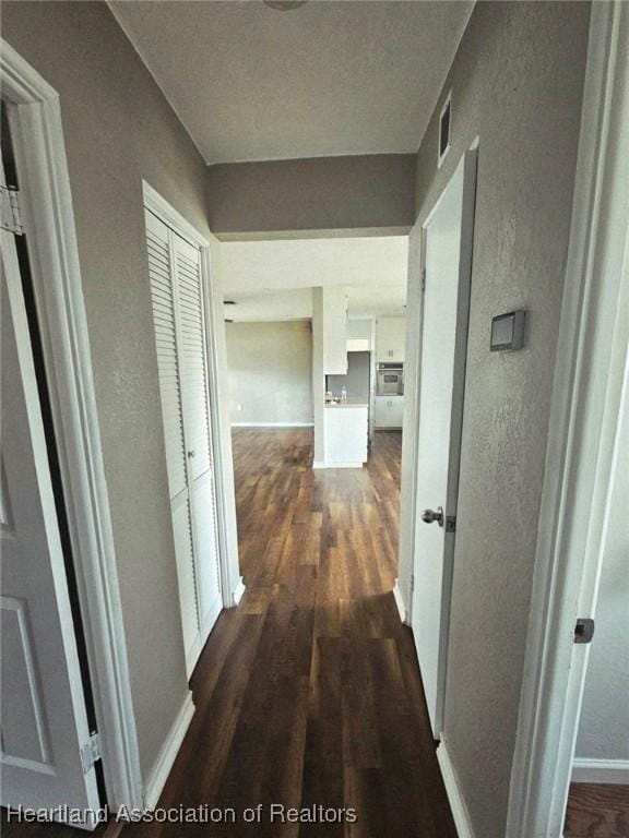 908 Taseschee Dr, Sebring, FL 33870 - hall with dark wood finished floors, baseboards, and a textured wall