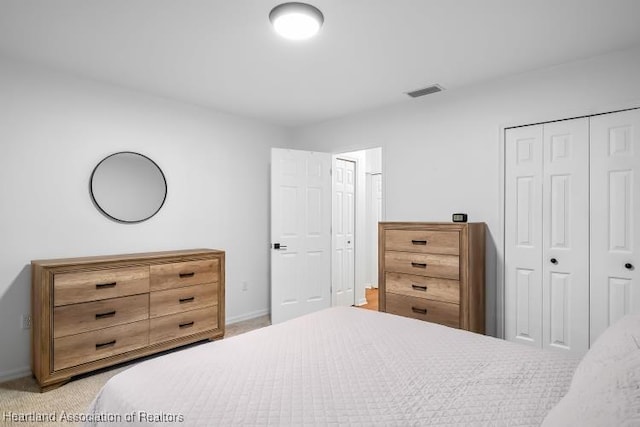 bedroom with a closet, visible vents, baseboards, and light carpet