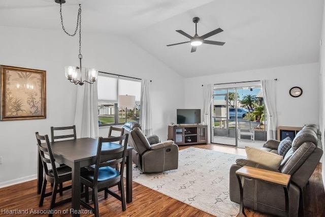 living area featuring baseboards, lofted ceiling, wood finished floors, and ceiling fan with notable chandelier