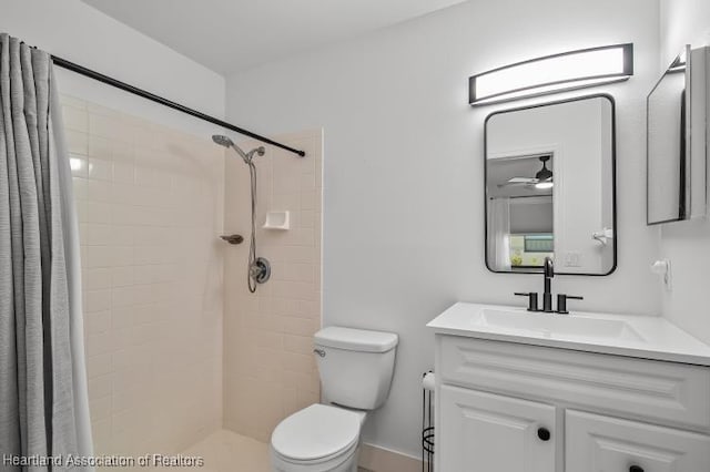 bathroom with a tile shower, toilet, vanity, and ceiling fan