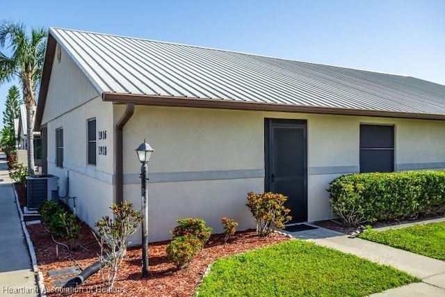 view of front of house featuring stucco siding, central air condition unit, a standing seam roof, and metal roof
