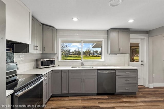 kitchen featuring dark wood-type flooring, sink, tasteful backsplash, gray cabinets, and stainless steel appliances