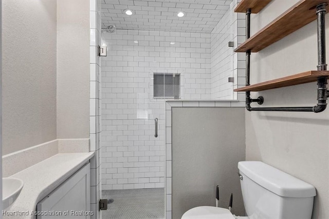 bathroom featuring vanity, a shower with door, and toilet