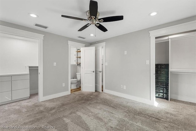 unfurnished bedroom featuring connected bathroom, a spacious closet, ceiling fan, light carpet, and a closet