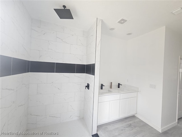 bathroom with a tile shower, vanity, and hardwood / wood-style flooring