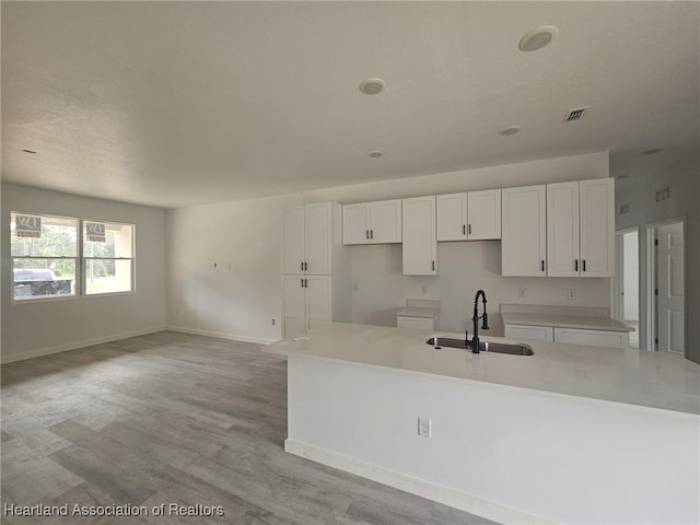 kitchen featuring light hardwood / wood-style flooring, a center island with sink, white cabinetry, and sink