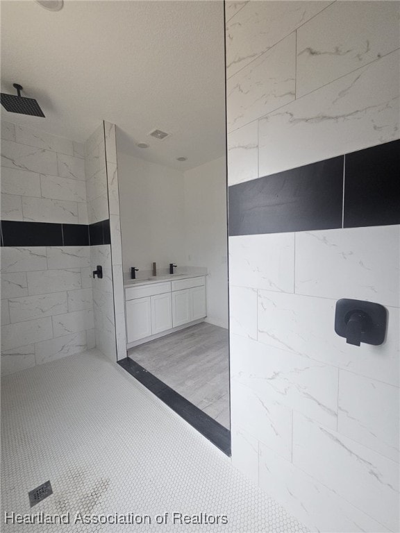 bathroom featuring a tile shower and vanity