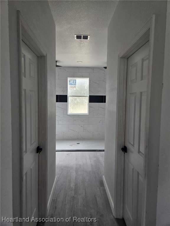 hall with a textured ceiling and hardwood / wood-style flooring