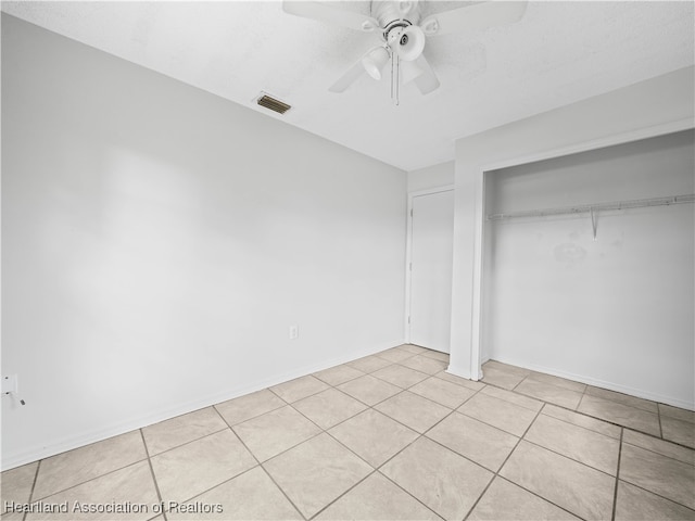 unfurnished bedroom featuring ceiling fan, a closet, light tile patterned floors, and a textured ceiling