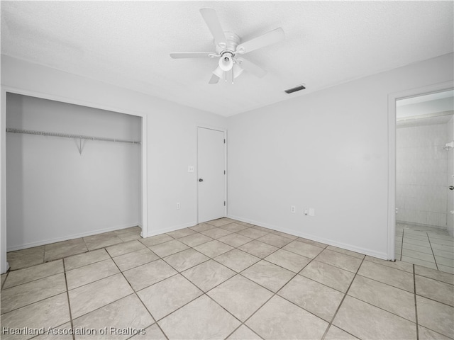 unfurnished bedroom with a textured ceiling, a closet, ceiling fan, and light tile patterned flooring