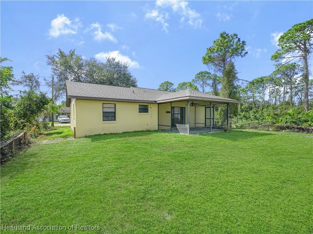 back of property with a yard and a sunroom