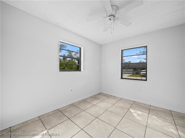 unfurnished room with ceiling fan, light tile patterned floors, and a textured ceiling