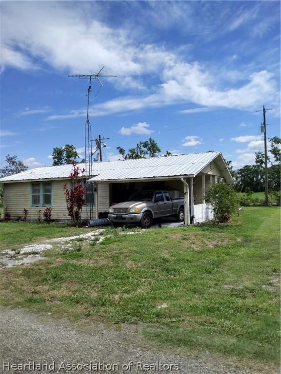single story home featuring a front lawn and a carport