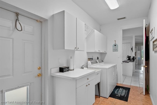 laundry area with cabinets, light tile patterned floors, and independent washer and dryer