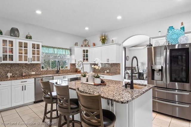 kitchen with white cabinetry, an island with sink, dark stone counters, and appliances with stainless steel finishes