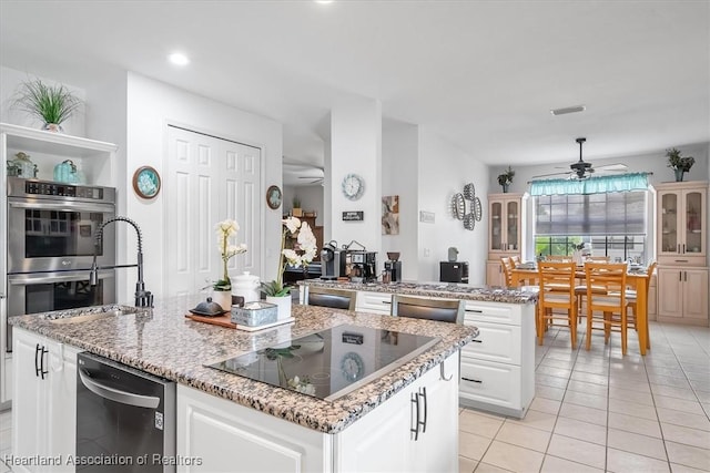 kitchen with sink, ceiling fan, white cabinetry, black appliances, and a kitchen island