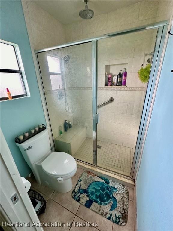 bathroom with tile patterned flooring, a shower with door, and toilet