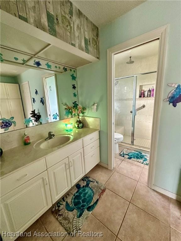 bathroom with vanity, toilet, a shower with door, tile patterned floors, and a textured ceiling