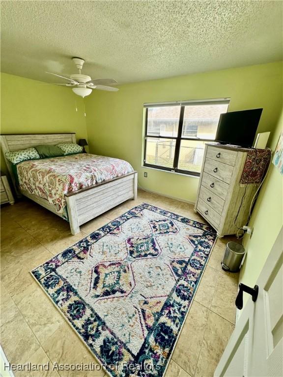 bedroom with ceiling fan and a textured ceiling