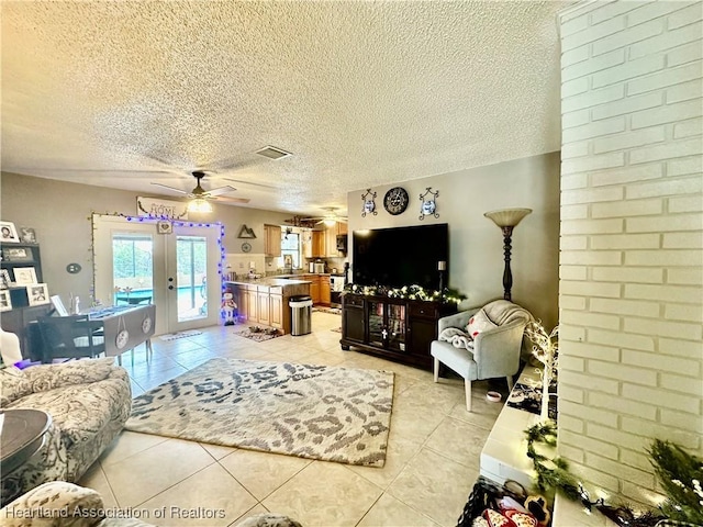 tiled living room featuring a textured ceiling, ceiling fan, and french doors