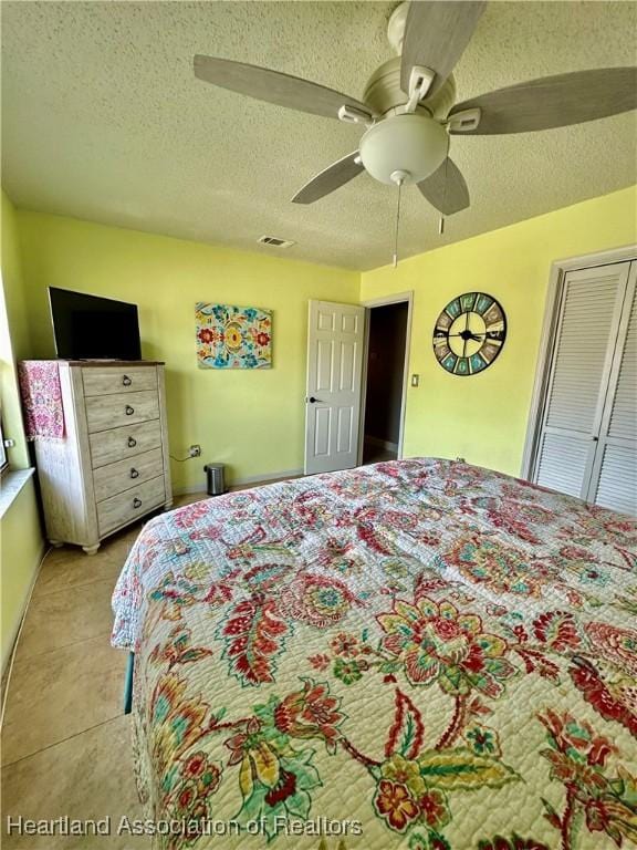 bedroom featuring light tile patterned flooring, ceiling fan, and a textured ceiling